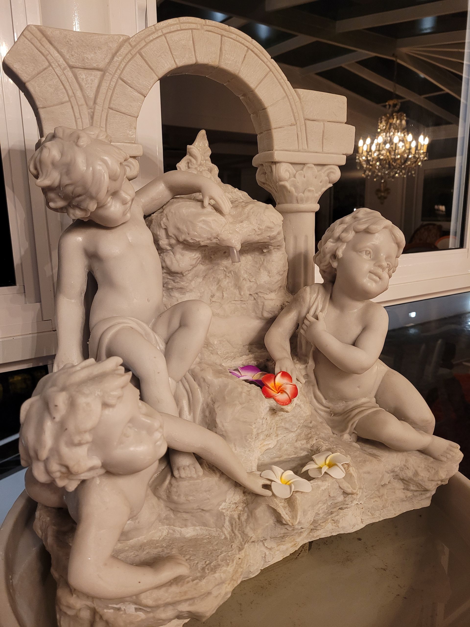 Uma estátua de três querubins está sobre uma mesa.