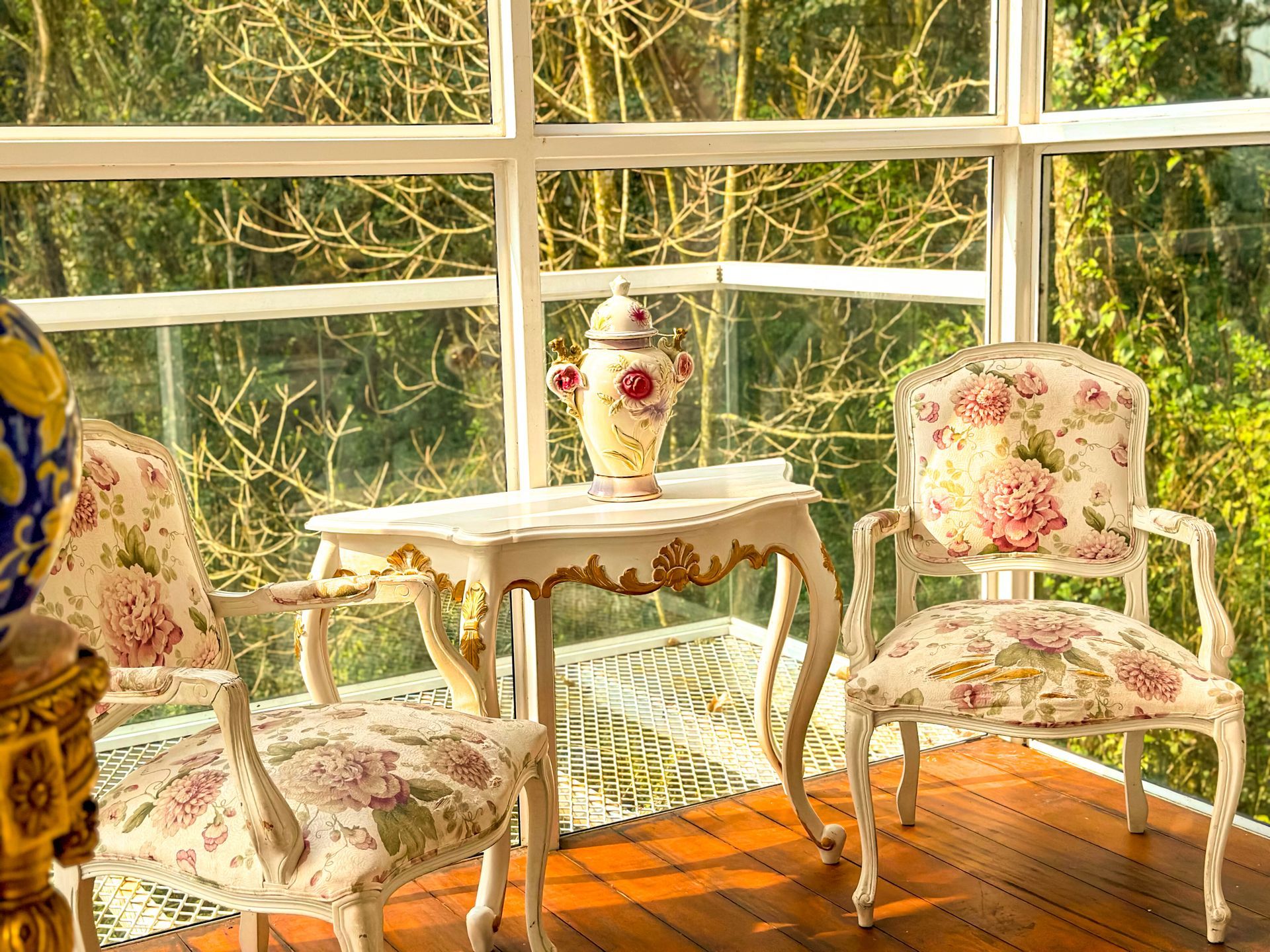 Uma mesa e cadeiras em uma varanda com vista para as árvores.