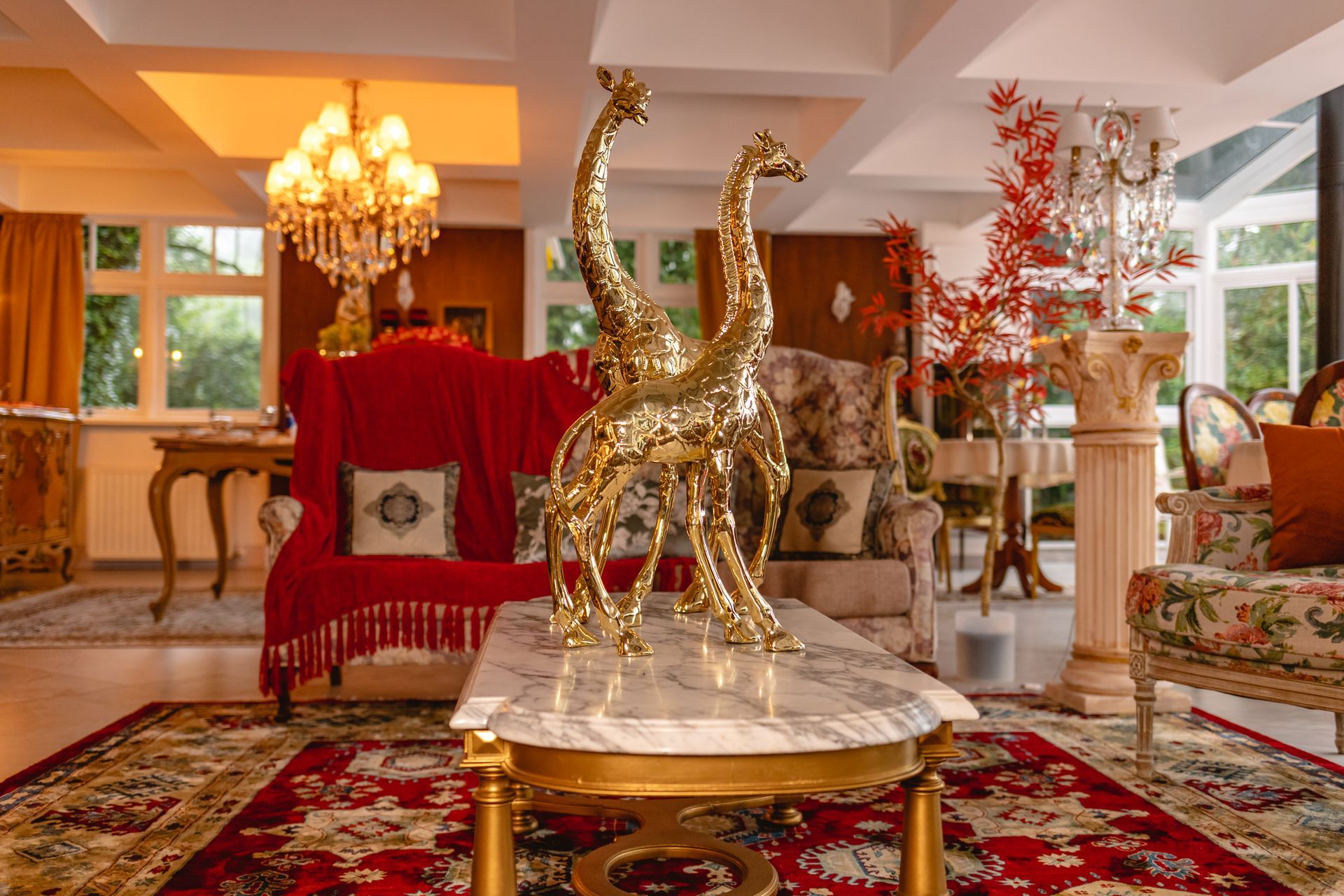 Uma sala de estar com um sofá, cadeiras, uma mesa e um lustre.