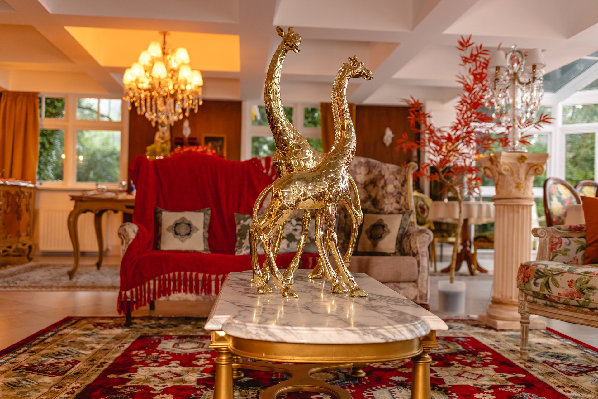 Uma sala de estar com um sofá, cadeiras e uma mesa com duas estátuas de girafas.