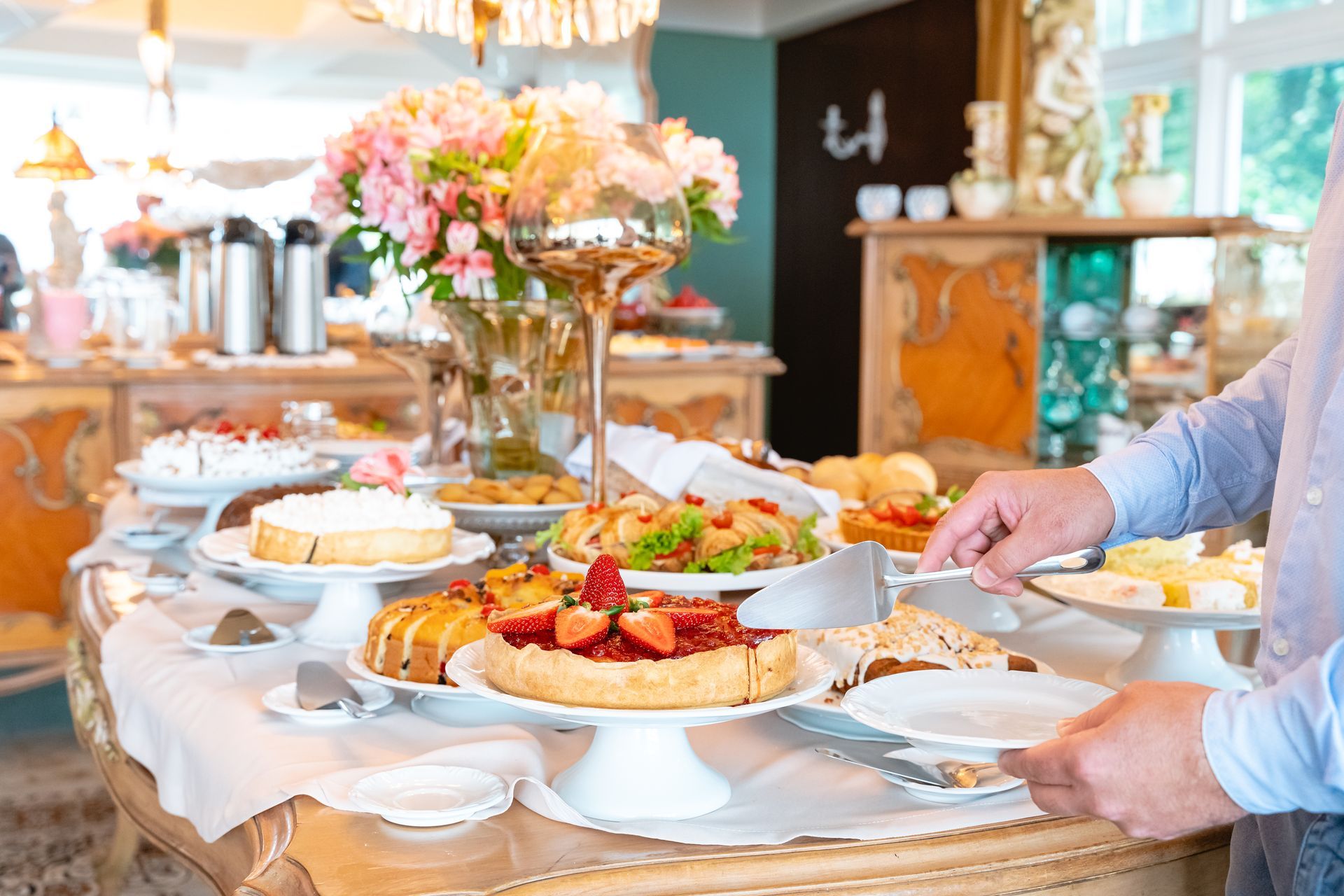 Um homem está pegando um prato de comida de uma mesa de bufê.