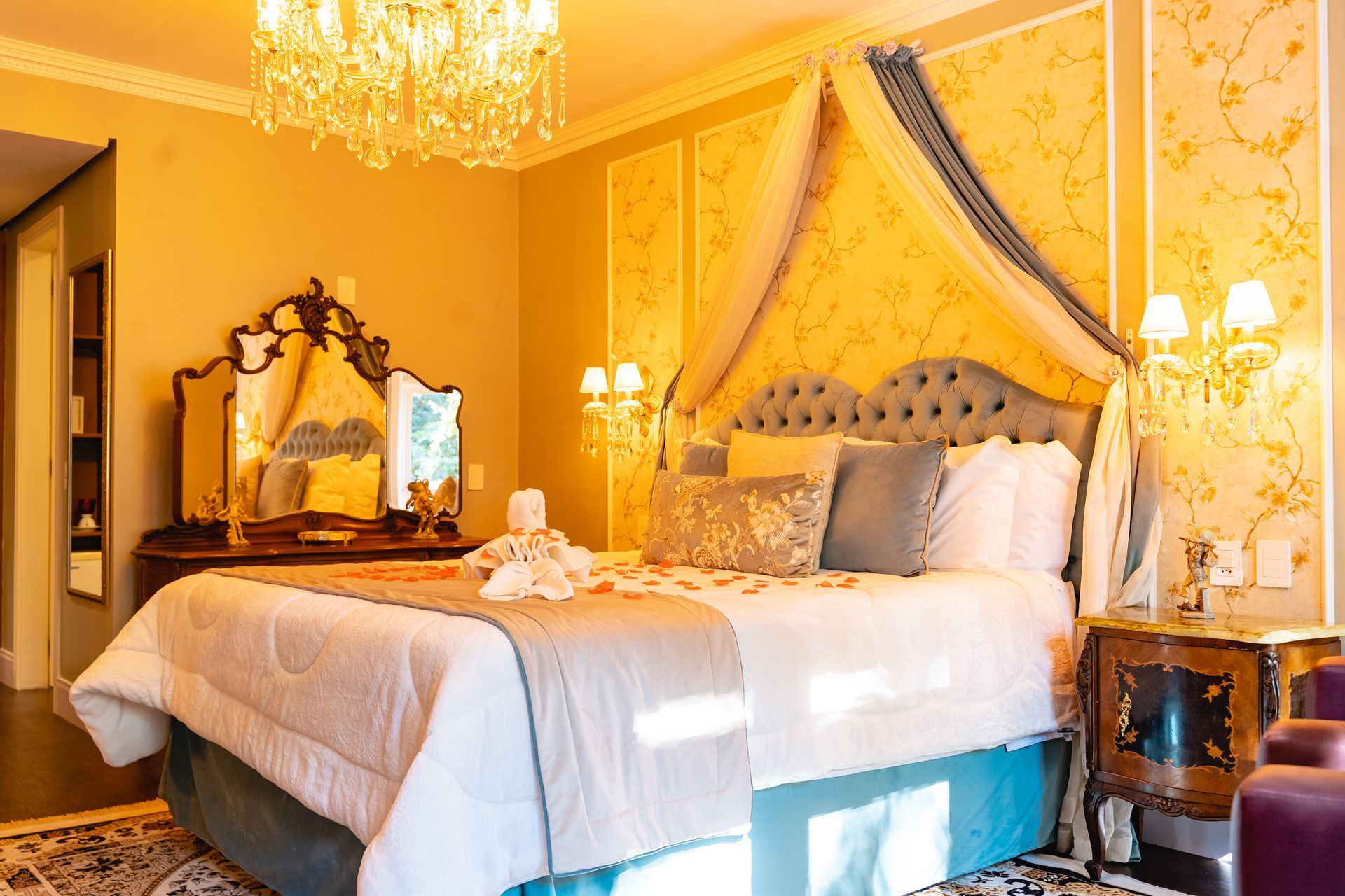 Um quarto com cama, mesa de cabeceira, espelho e lustre.