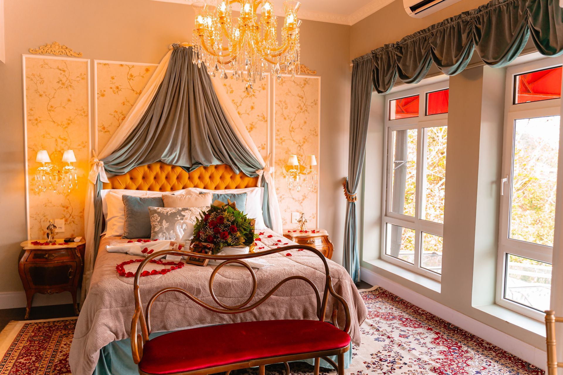 Há uma cama com dossel e um banco no quarto.