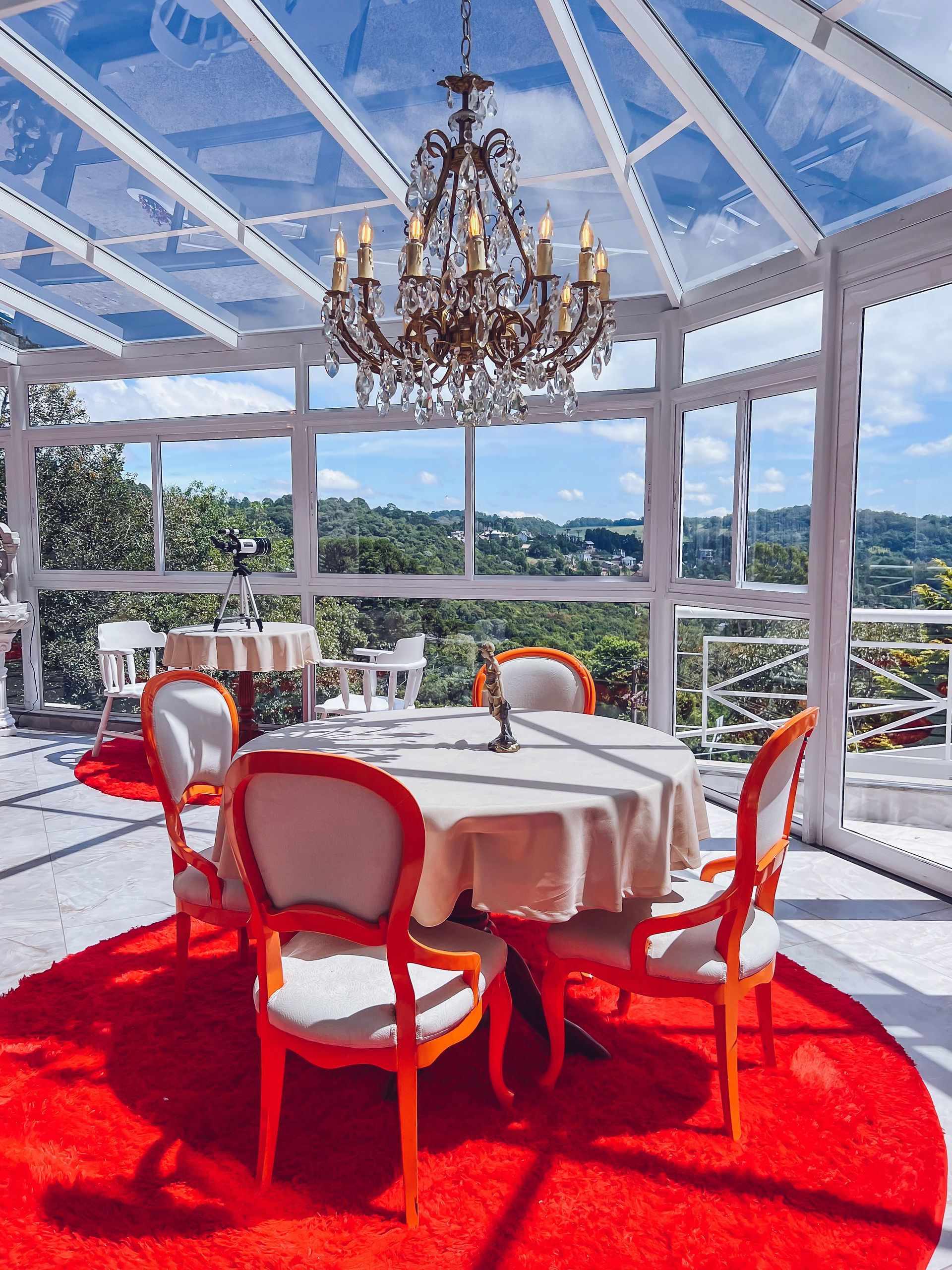 Uma sala de jantar com uma mesa redonda e cadeiras e um lustre pendurado no teto.