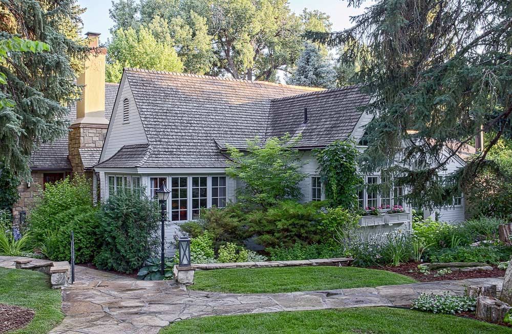 A large house with a stone walkway leading to it is surrounded by trees.
