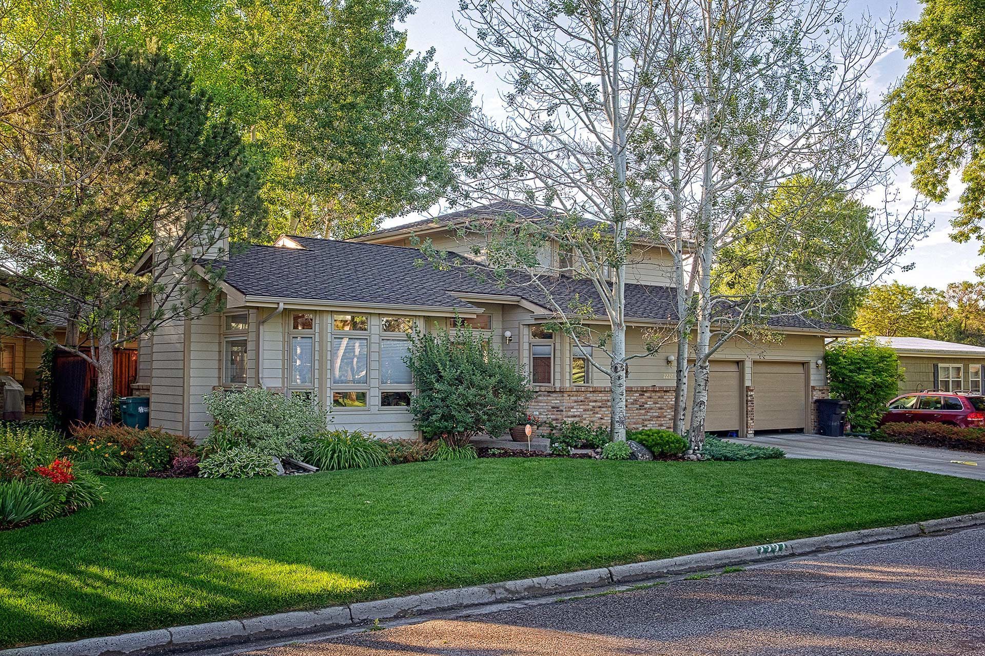 A house with a large lawn and trees in front of it.