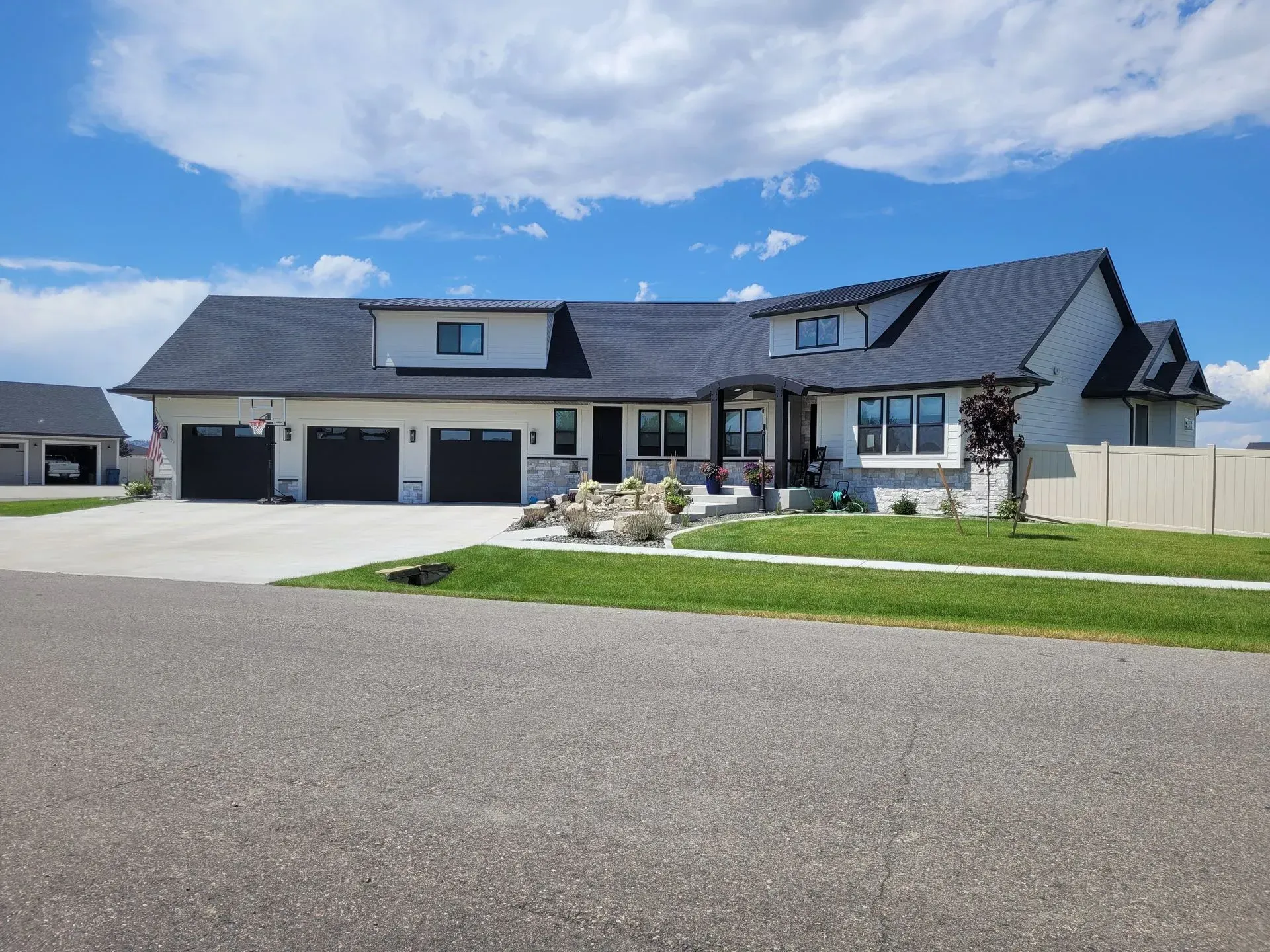 A large white house with a black roof is sitting on top of a lush green lawn.