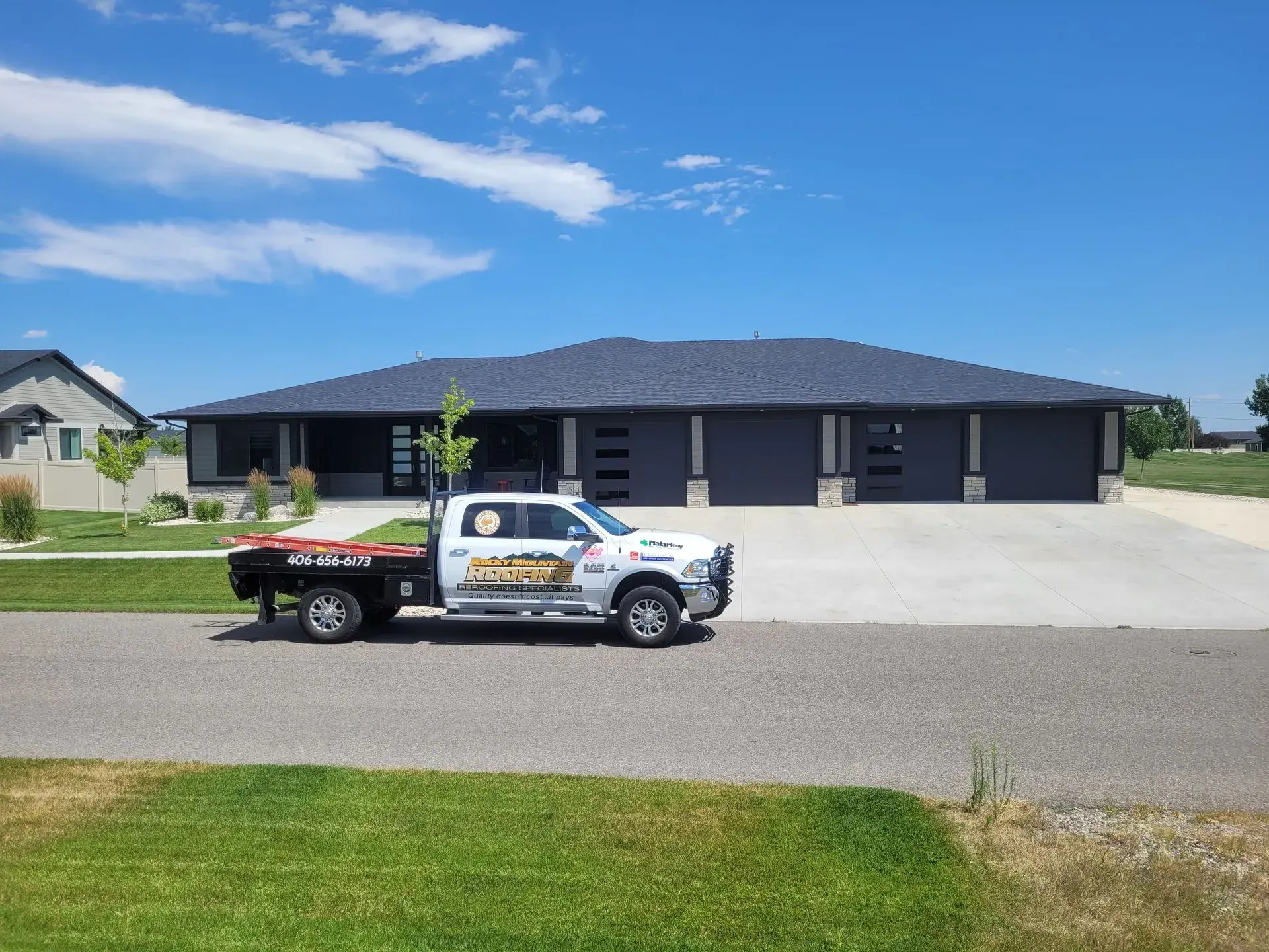 A white tow truck is parked in front of a large house.