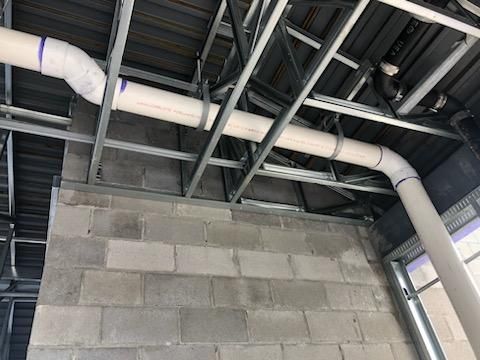 A building under construction with pipes coming out of the ceiling.