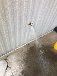 A person is spraying water from a hose on a wall.