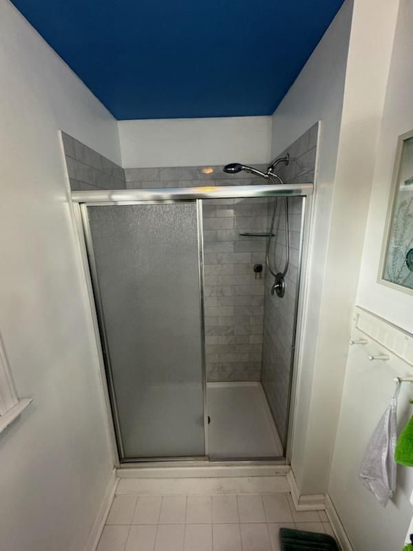 A bathroom with a sliding glass shower door and a blue ceiling.