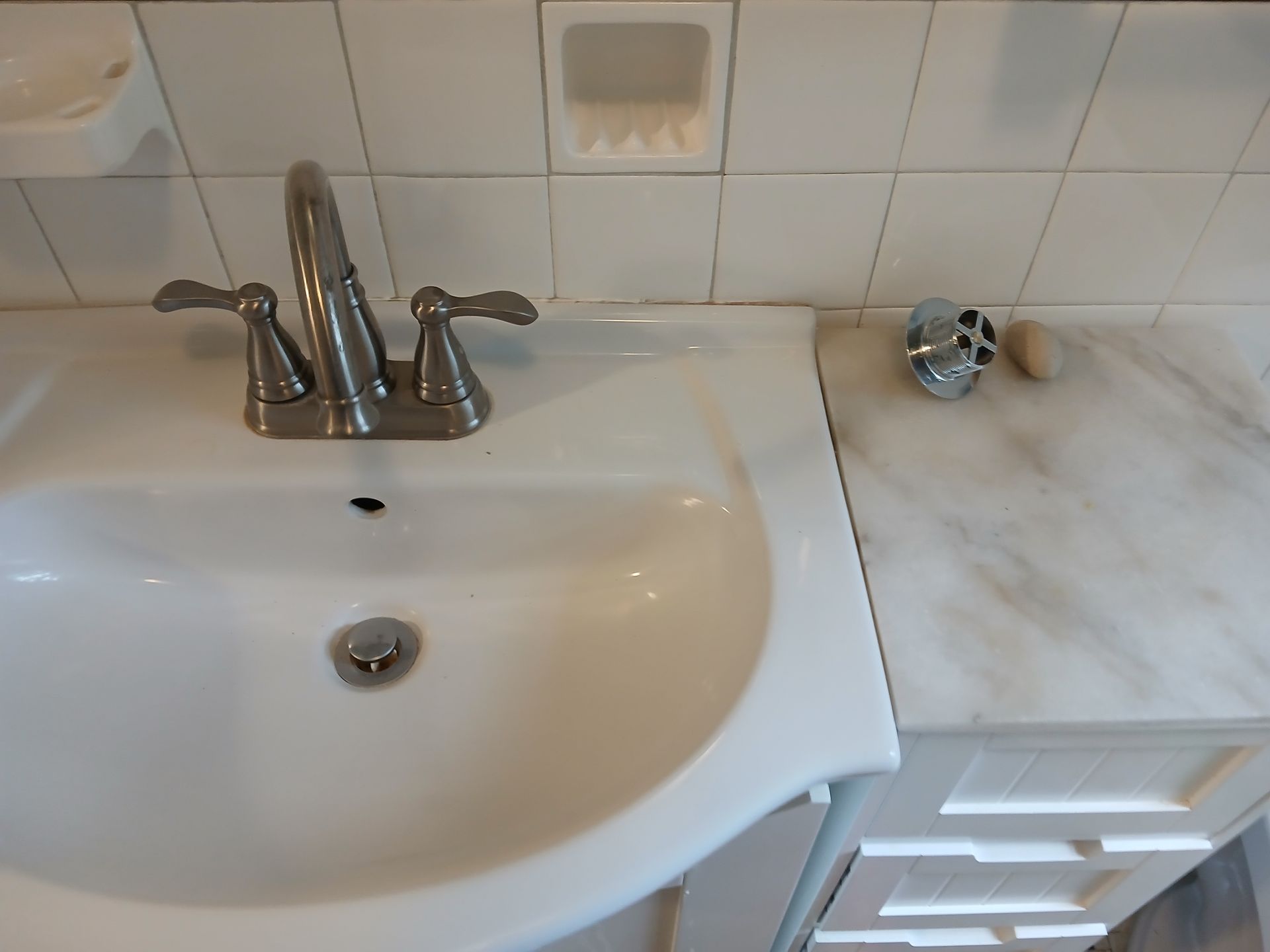 A bathroom sink with a soap dish next to it
