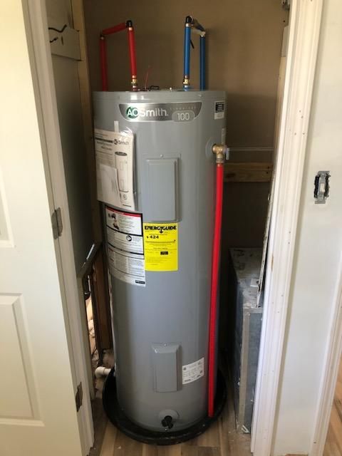 A water heater is sitting in a closet next to a door.