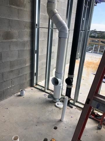 A ladder is sitting next to a pipe in a room.