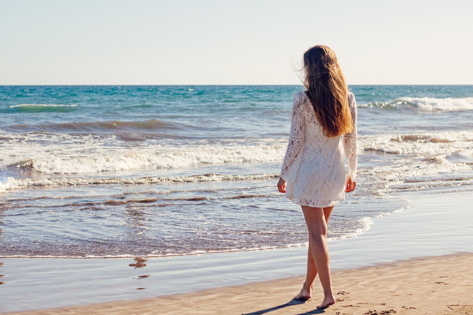 A young woman walking on the beach in the surf line