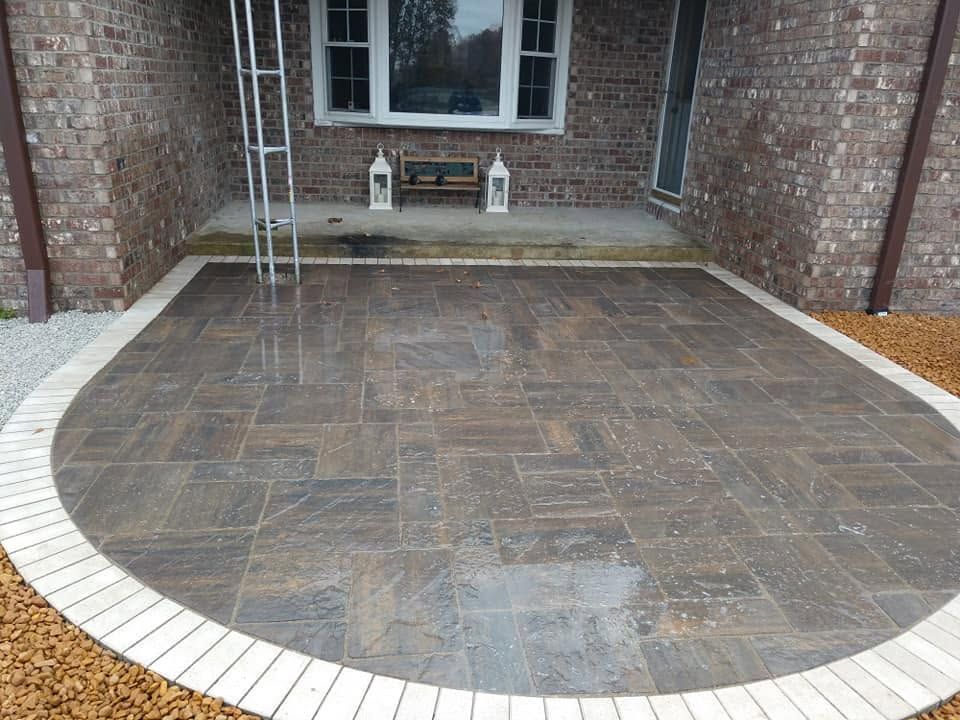 Finished custom flagstone patio installation alongside a residential brick house.