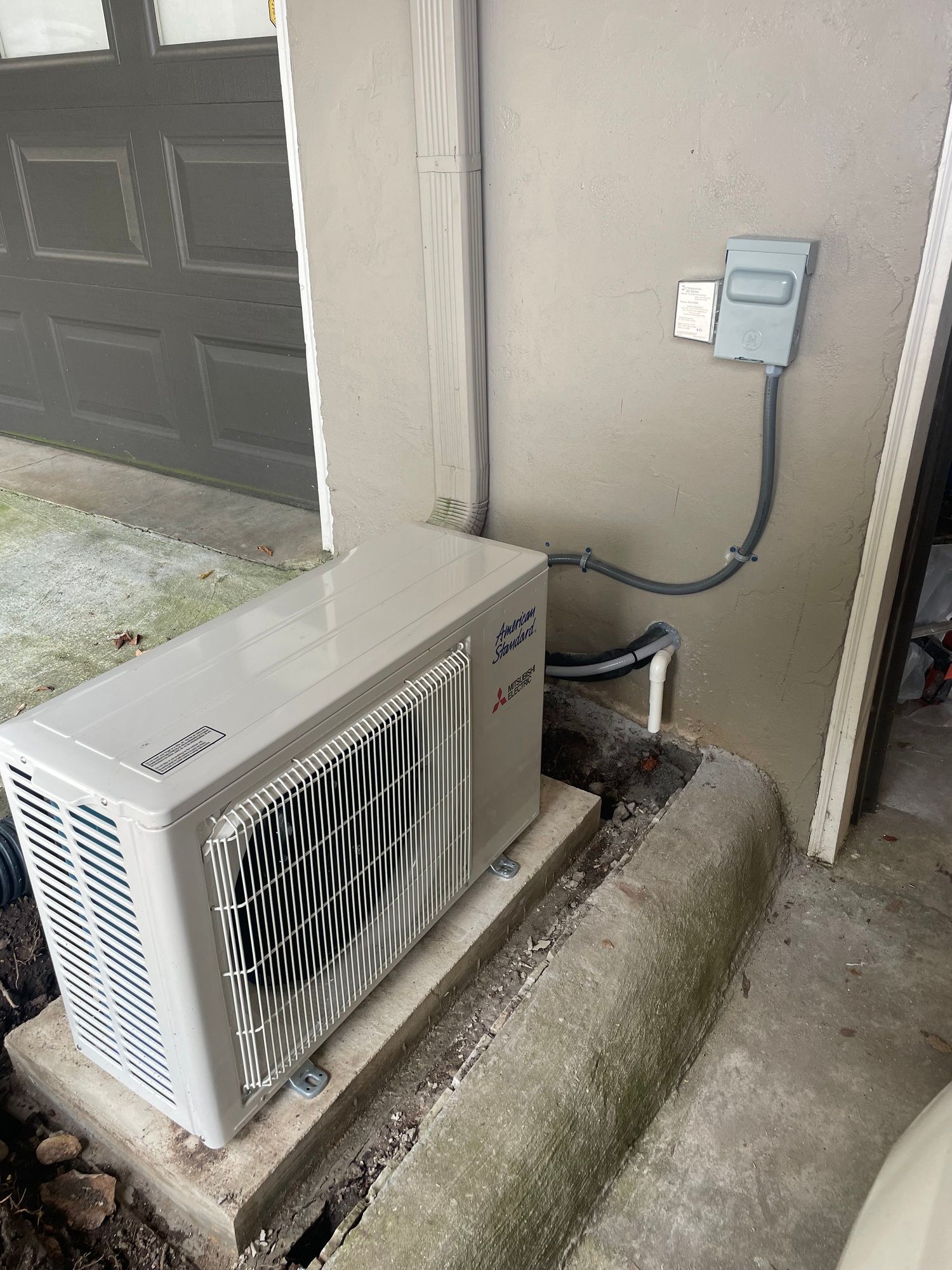 a white air conditioner is sitting on the side of a building next to a door .