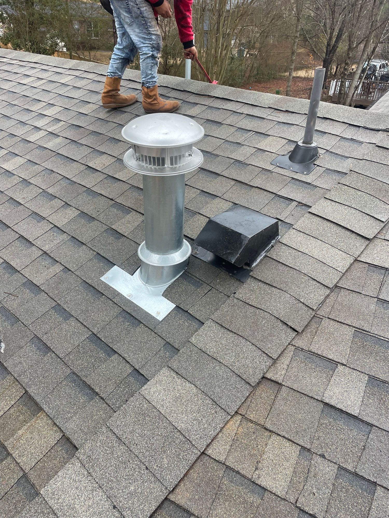 a person is standing on top of a roof with a chimney .