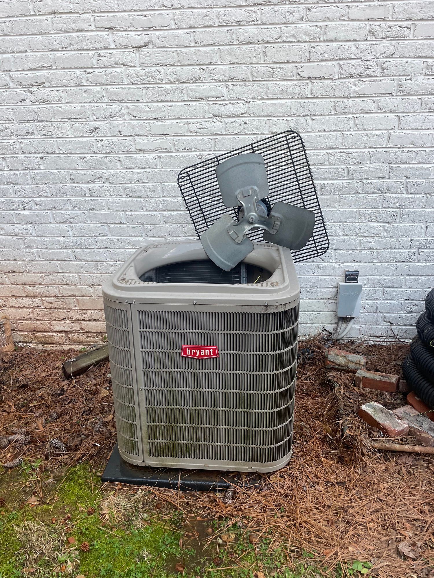 a broken air conditioner is sitting in front of a white brick wall .