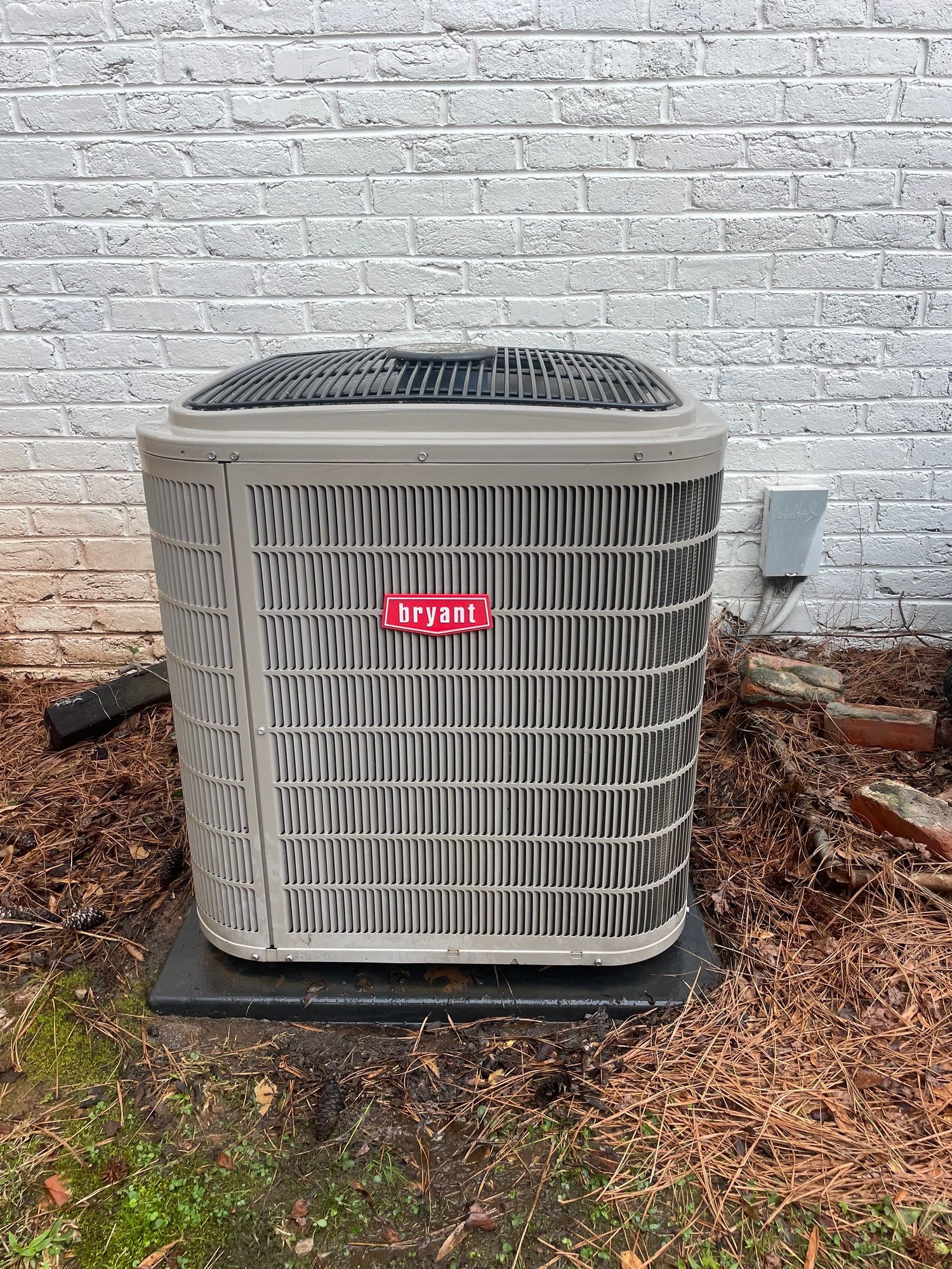 an air conditioner is sitting in front of a white brick wall .