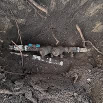 A pipe is laying in the dirt in a hole.
