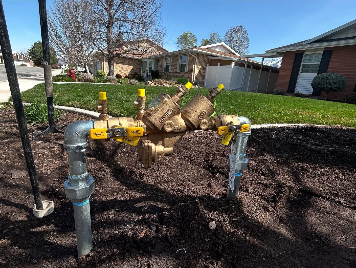 A gas valve is sitting in the dirt in front of a house.