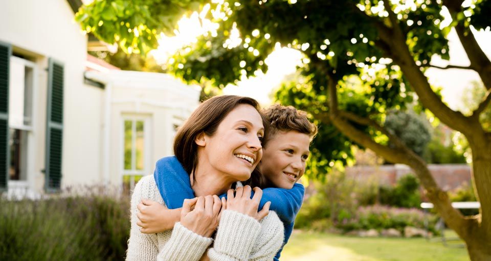happy mother and son outside under tree