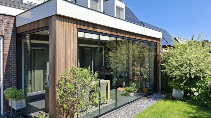 Een huis met een grote glazen veranda en glazen schuifdeuren.