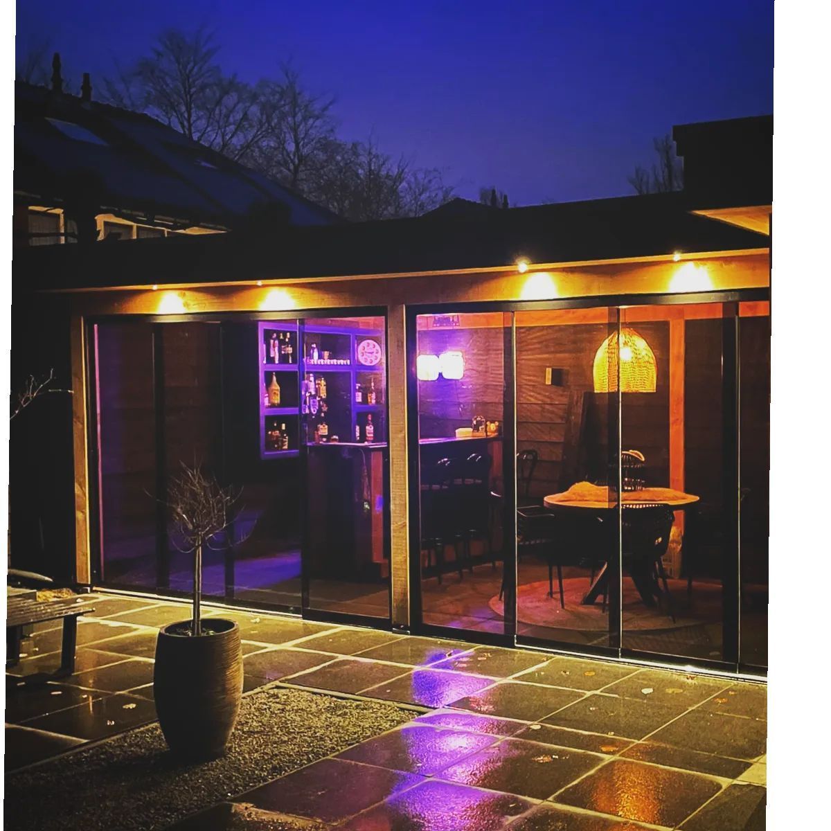 Een foto van een huis met glazen schuifdeuren 's nachts