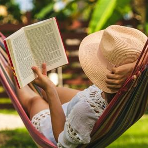 Een vrouw ligt in een hangmat een boek te lezen.