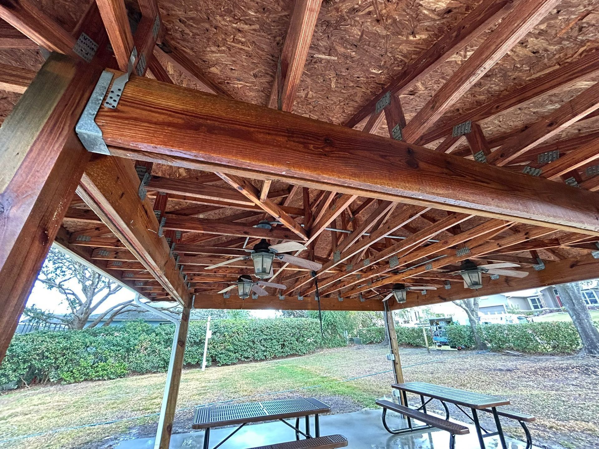A wooden gazebo with a picnic table underneath it.