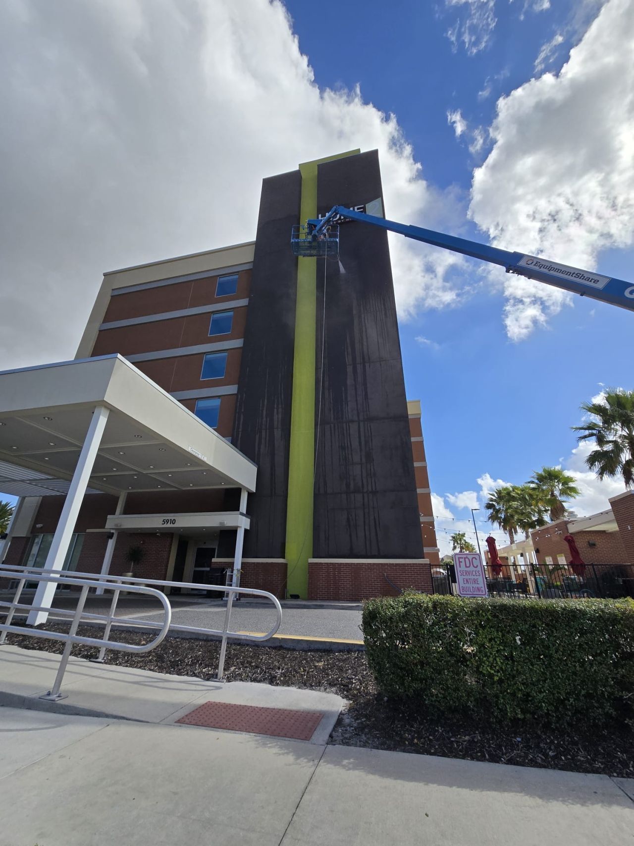 A large building is being cleaned with a crane.