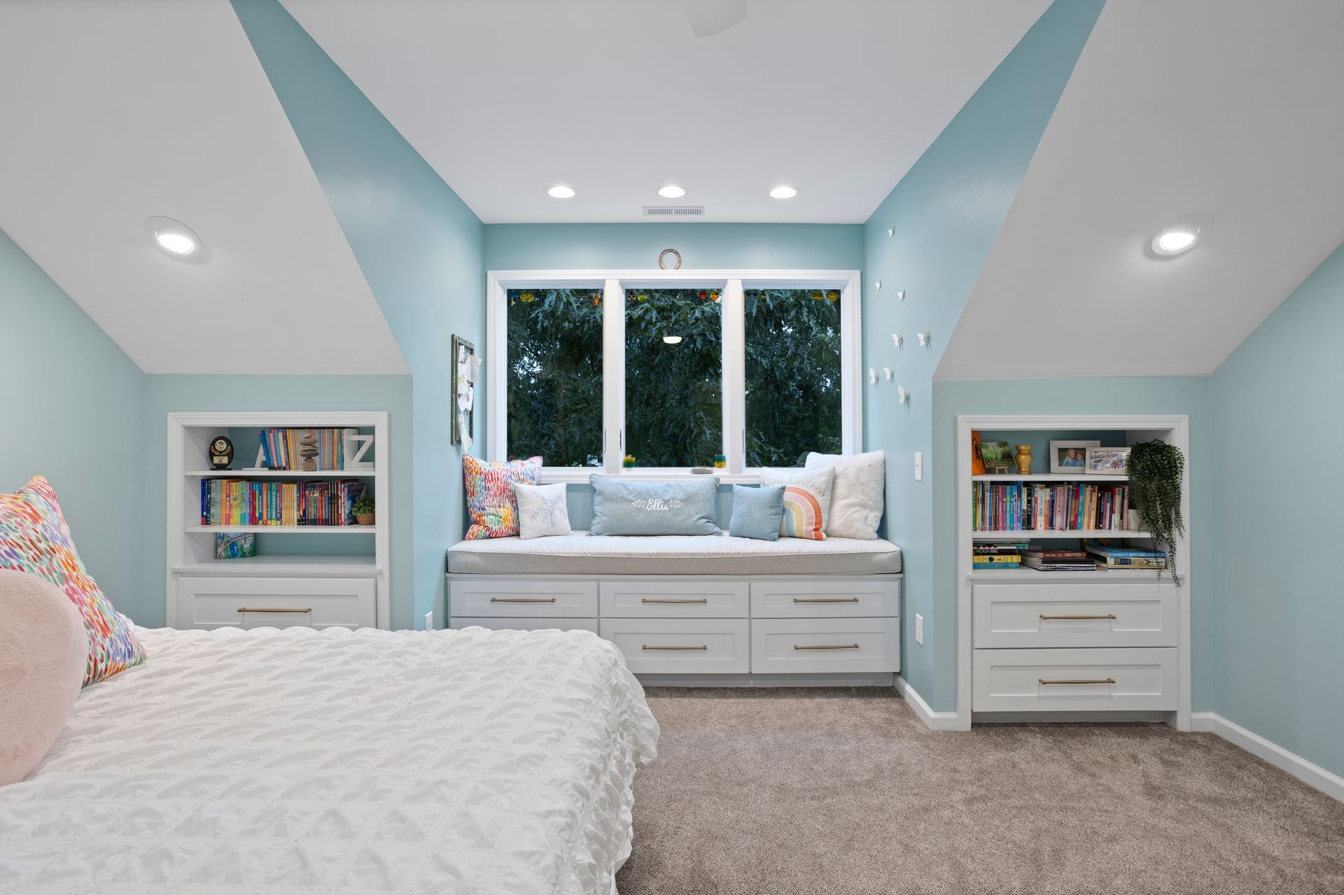 Bedroom with built-in window seat, bookshelves, and light blue walls built by Nunley Custom Homes in Greenville, SC.