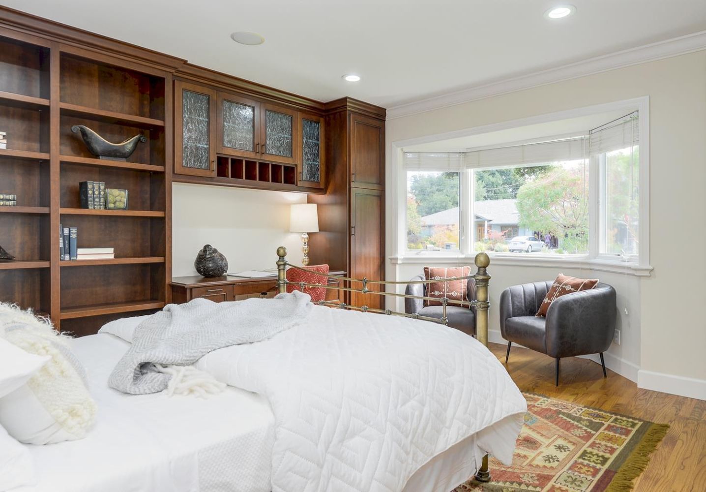 Bedroom with built-in bookshelves, desk, bed, bay window, armchair, and hardwood floors built by Nunley Custom Homes in Greenville, SC.