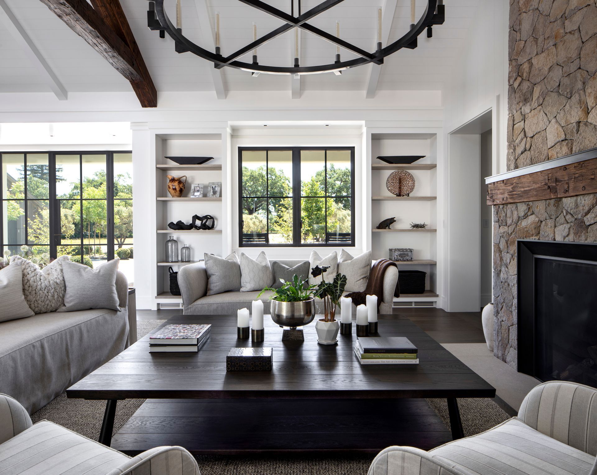 Living room with sofas, coffee table, fireplace, built-in shelves, and a large window built by Nunley Custom Homes in Greenville, SC.