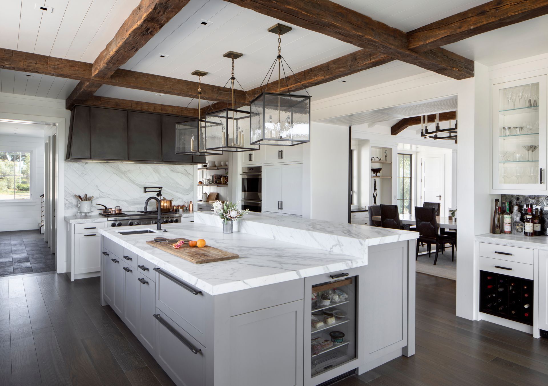 Modern kitchen with gray island, marble countertops, wood beams remodeled by Nunley Custom Homes in Greenville, SC.