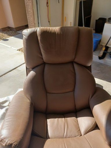 A brown leather recliner is sitting in a garage.