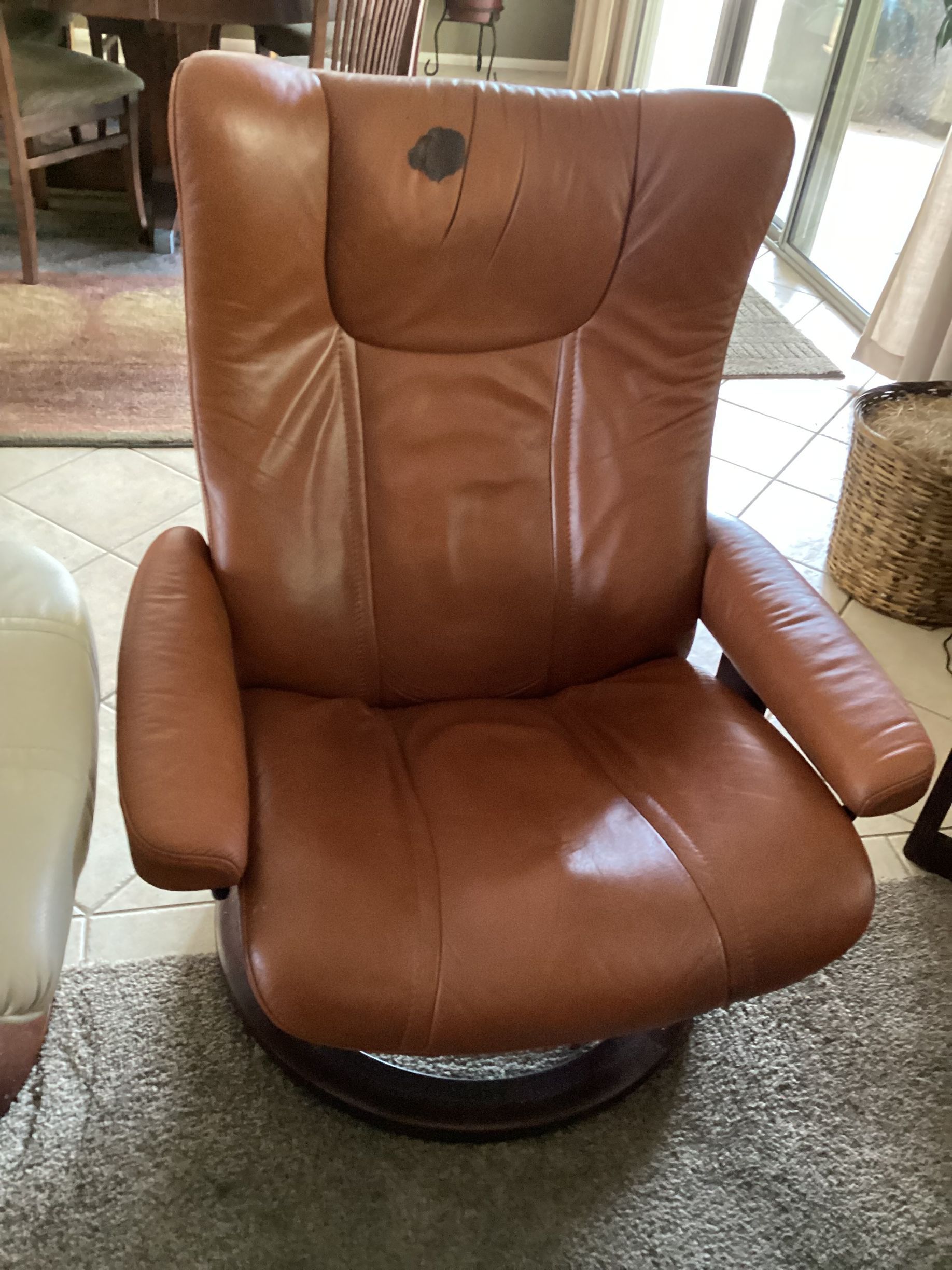 A brown leather chair is sitting on a rug in a living room.
