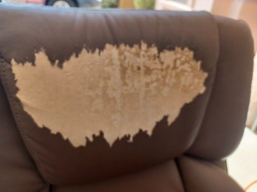 A brown leather chair with a stain on it