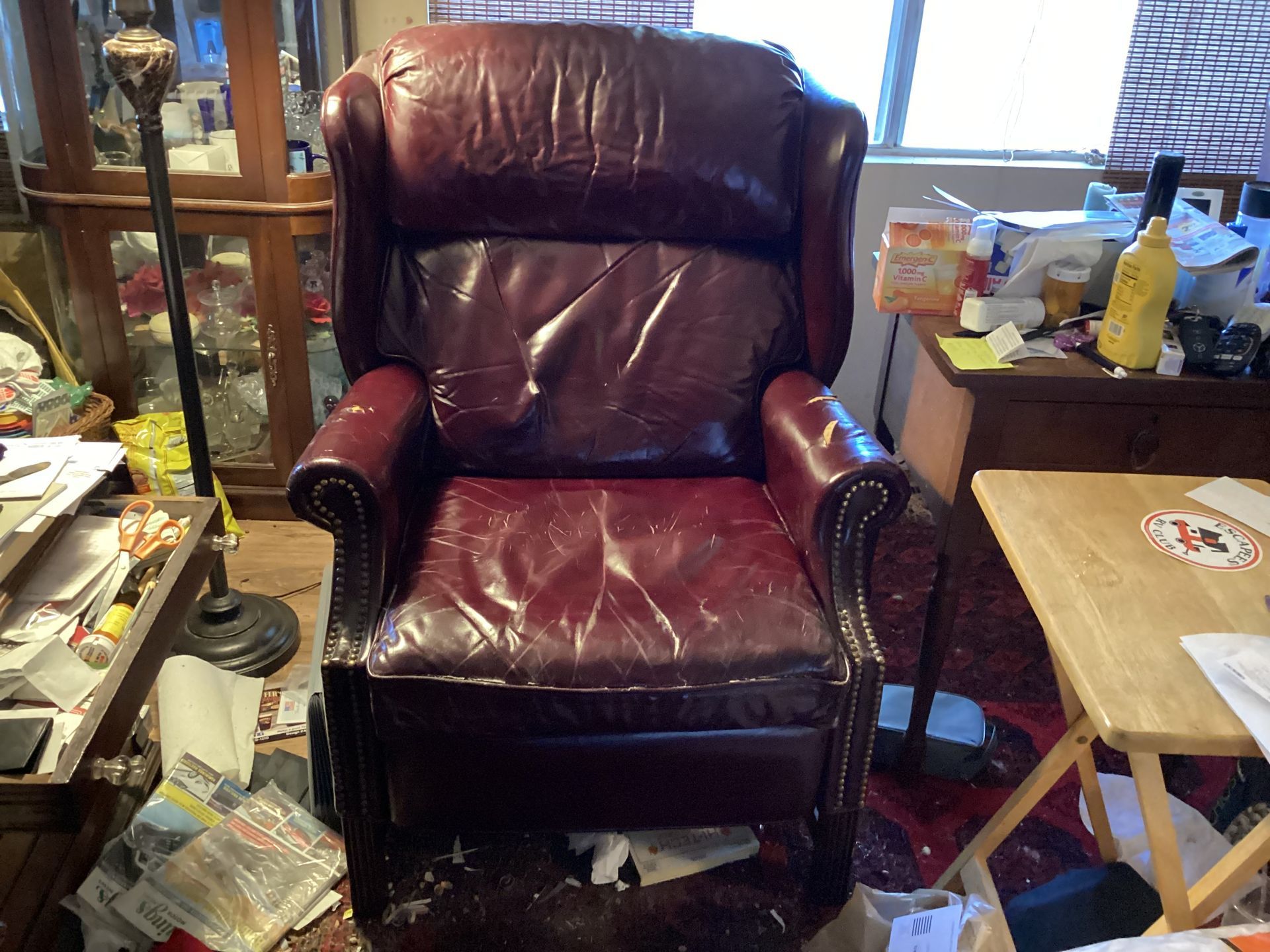 A red leather chair is sitting in a messy room