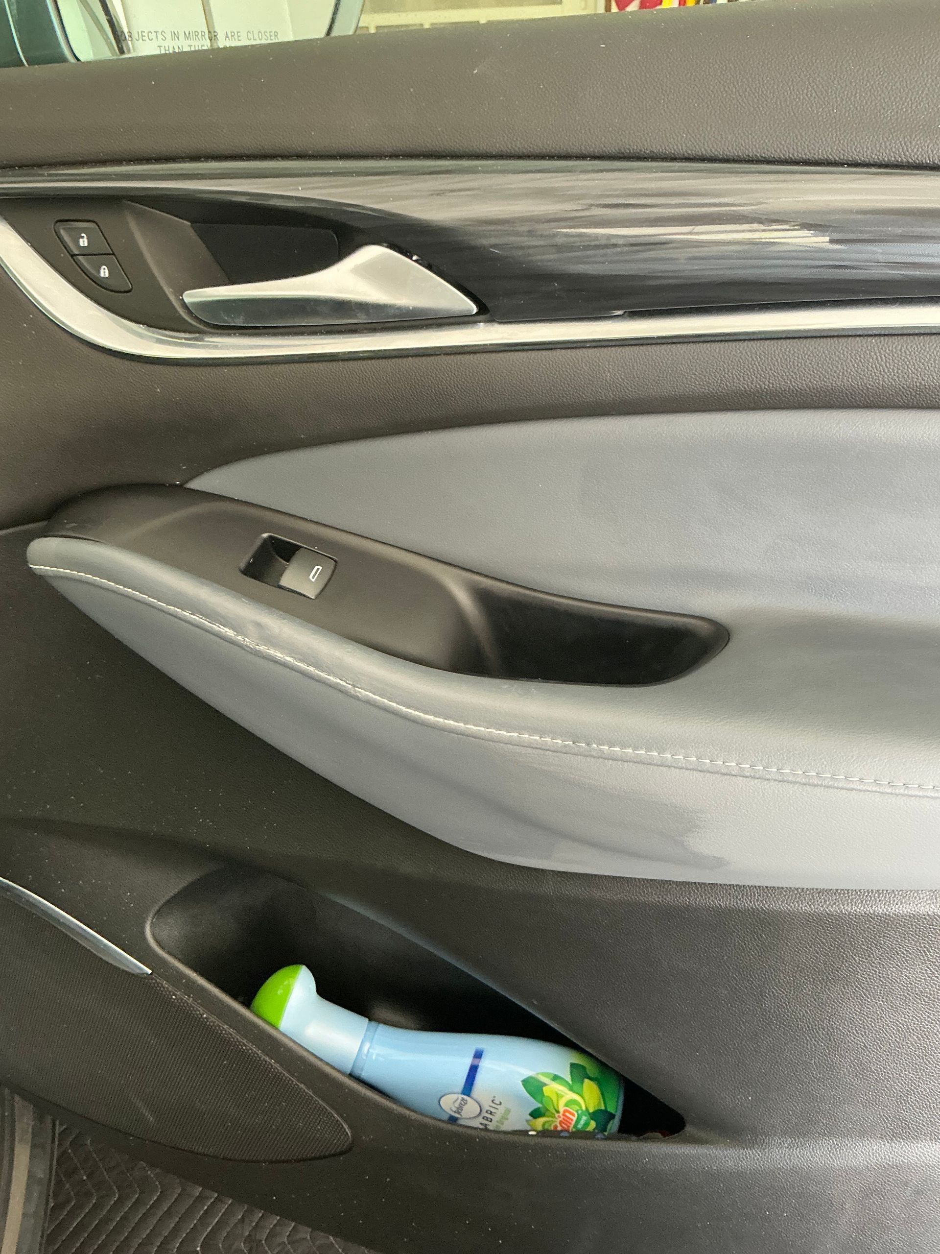 A bottle of shampoo is in the door pocket of a car.