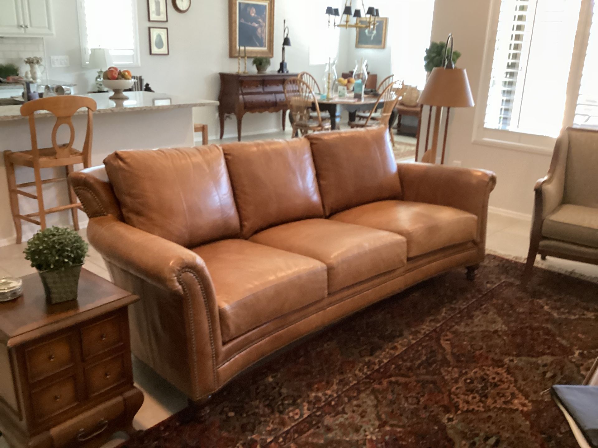 A living room with a brown leather couch and chairs