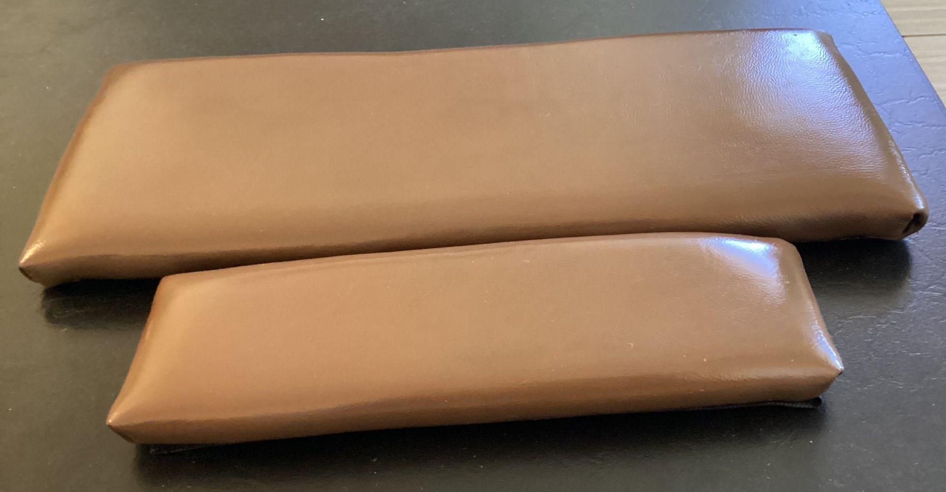Two brown pieces of leather are sitting on a table.