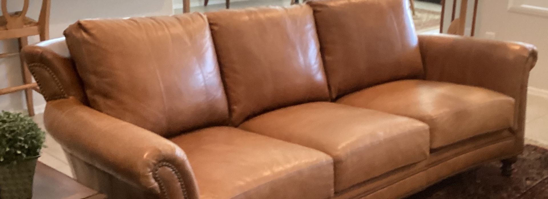 A brown leather couch is sitting on a rug in a living room.