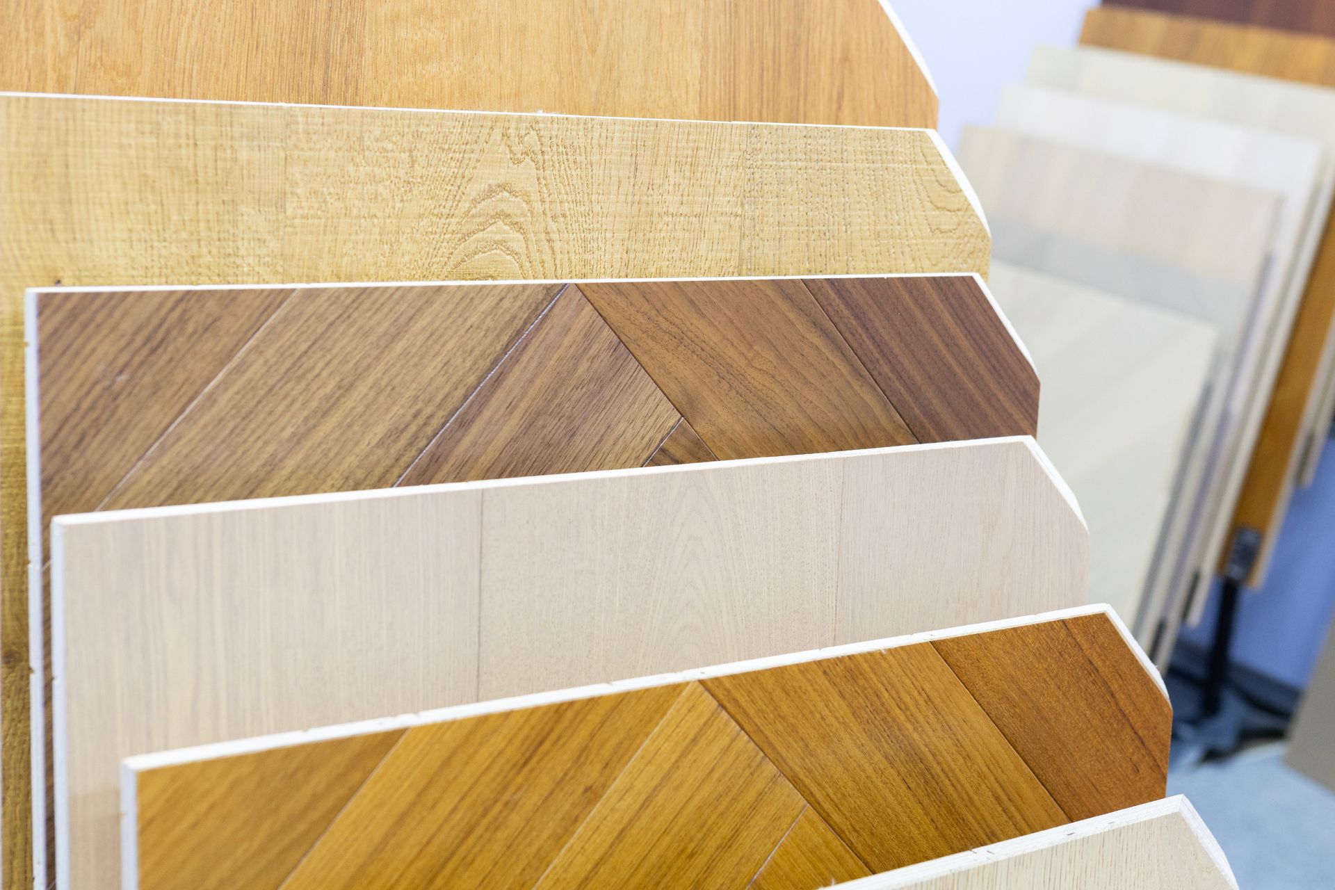 Display of assorted wood flooring samples in various tones and patterns arranged on angled showroom racks.
