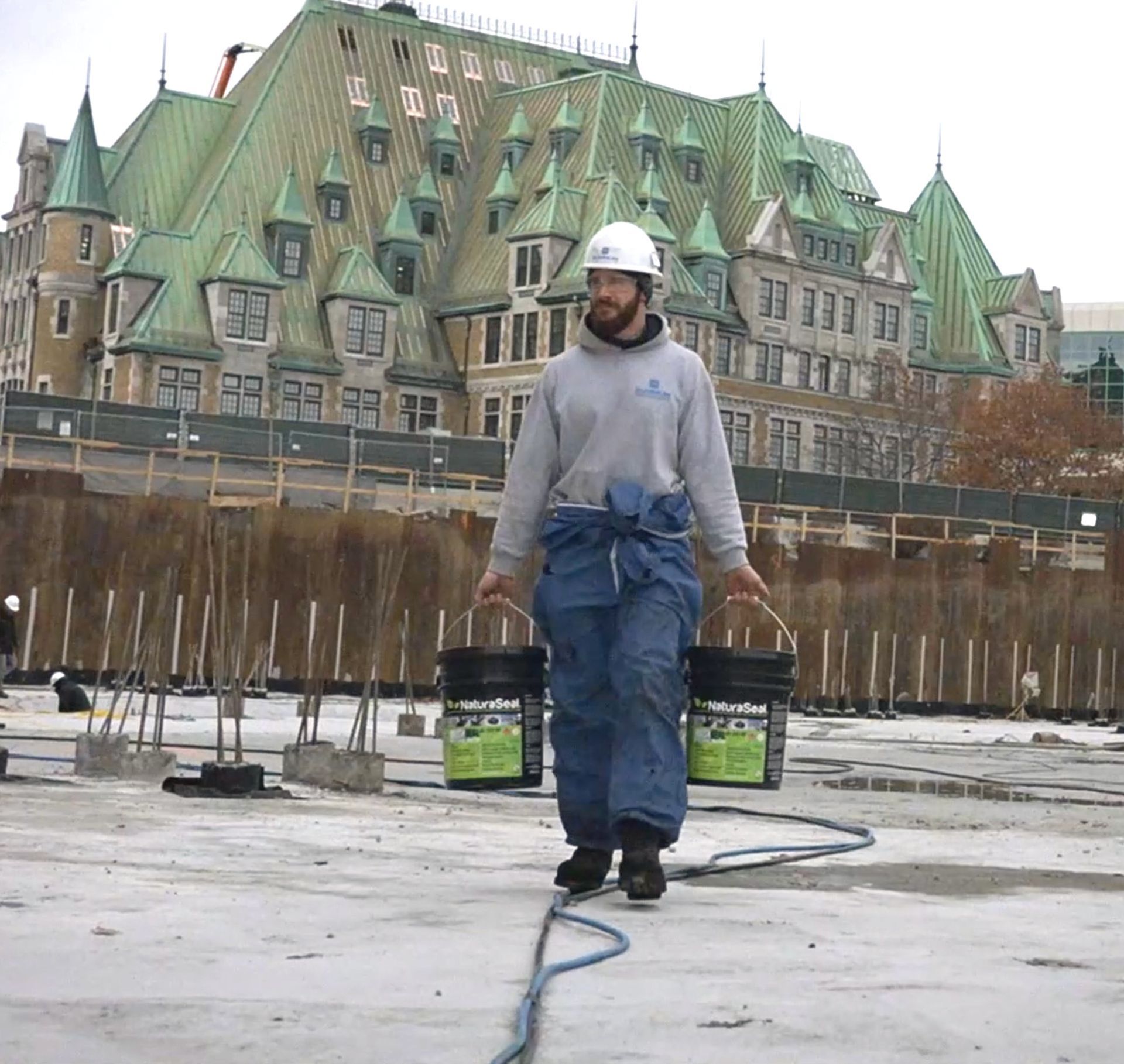 Un homme portant un casque transporte deux seaux de peinture