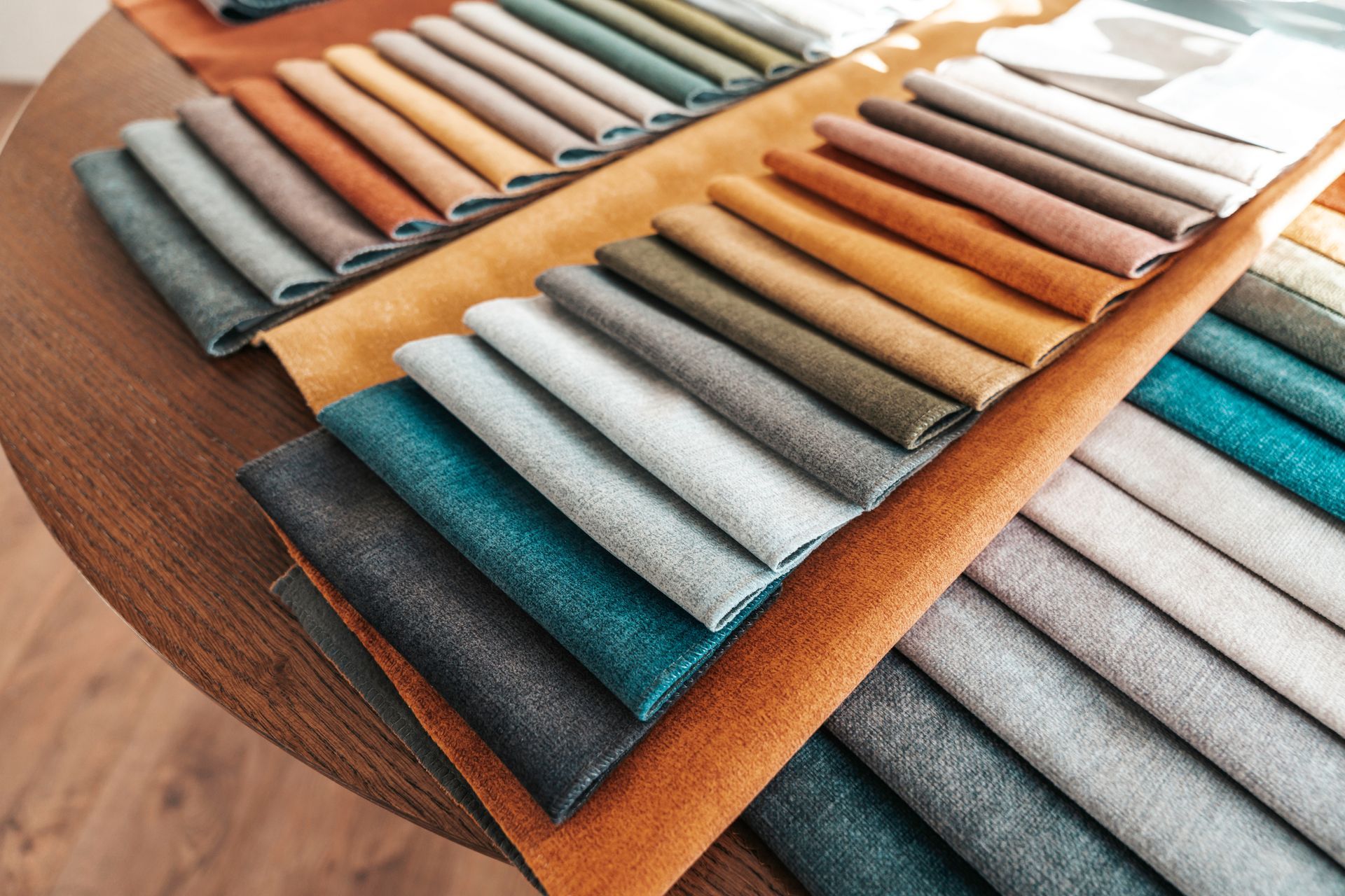 Swatches of colorful upholstery fabric neatly arranged on a wooden table.