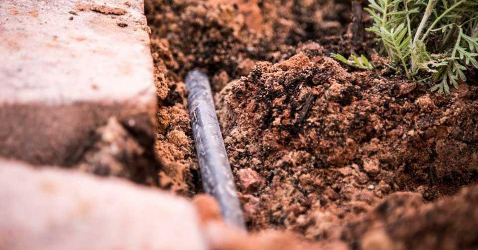 A close up of a pipe in the ground next to a brick.