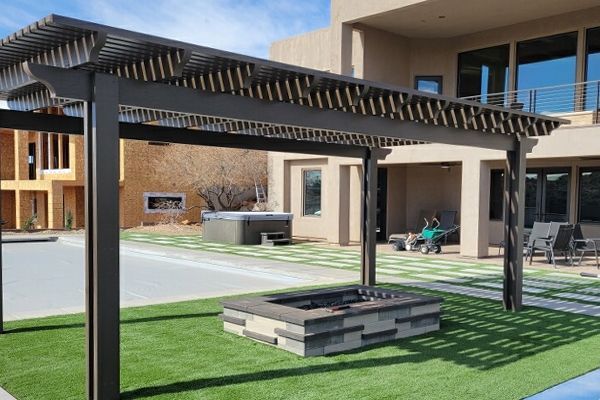 A large house with a pergola and a fire pit in front of it.