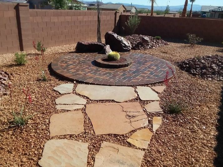 A stone walkway leading to a fire pit in a backyard